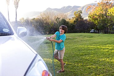 South Africa, Stanford, Boy (8-9) washing SUV on large green lawn