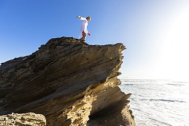 South Africa, Hermanus, Teenage girl (16-17) standing on cliff and looking at sea