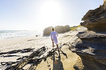 South Africa, Hermanus, Teenage girl (16-17) walking on sea coast at sunny day