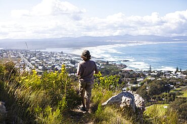 South Africa, Hermanus, Boy (8-9) looking at sea coast from hiking trail in mountains
