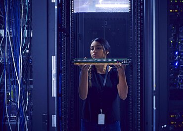 Female technician holding hard drive in server room