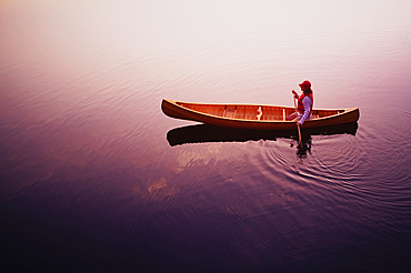 High angle view of woman paddling canoe on Lake Placid at sunrise, Adirondacks State Park