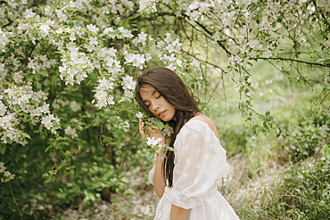 Portrait of teenage girl (16-17) with blooming apple tree