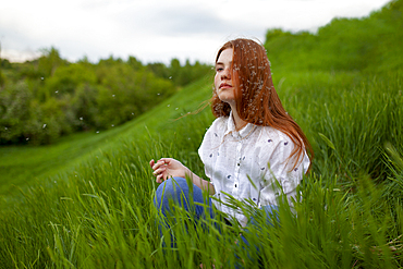 Portrait of serious teenage girl (16-17) sitting on grass