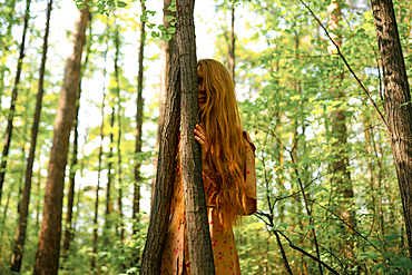 Young woman touching tree in forest