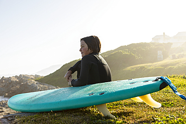 Boy (10-11) with surfboard sitting on Kammabaai Beach