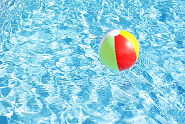 Beach ball floating on water in swimming pool