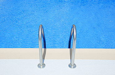 Swimming pool ladder railings and blue water