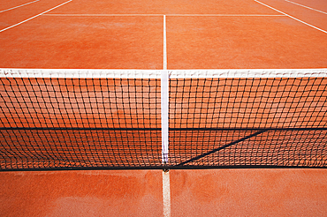 Tennis net on empty clay tennis court