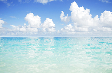 Puffy clouds over calm Caribbean sea surface
