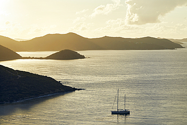 Sailboat anchored on calm bay at sunrise