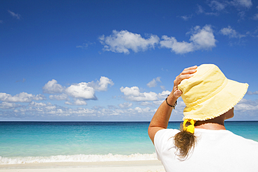 Rear view of woman in yellow hat facing sea