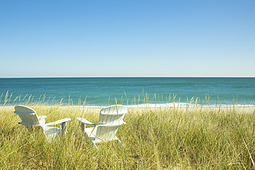 Pair of Adirondack chairs by beach