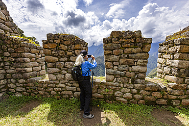 Woman hiker taking photos with smart phone at Machu Picchu