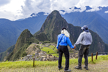 Rear view of couple facing Machu Picchu Inca ruins and mountains