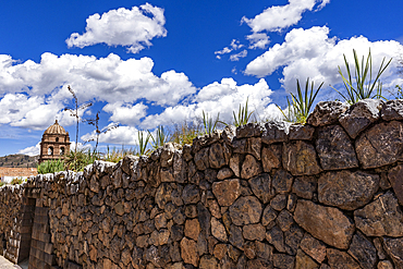 Puffy clouds above old stone wall