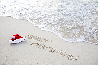 Santa hat and Christmas greetings written in beach sand, St. John, United States Virgin Islands, USA