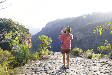 Rear view of woman photographing view of valley, Blackheath, New South Wales, Australia