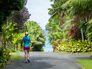Rear view of woman walking down road towards sea on Lord Howe Island, Lord Howe Island, New South Wales, Australia