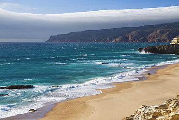 Ocean waves crashing on the sandy beach of Cascais, surrounded by cliffs, Estoril Coast, Lisbon, Portugal, Europe