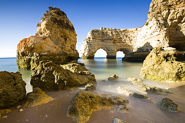 Sunrise on the cliffs and turquoise water of the ocean, Praia da Marinha, Caramujeira, Lagoa Municipality, Algarve, Portugal, Europe