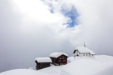 Snow covered mountain huts and church surrounded by low clouds, Bettmeralp, district of Raron, canton of Valais, Switzerland, Europe