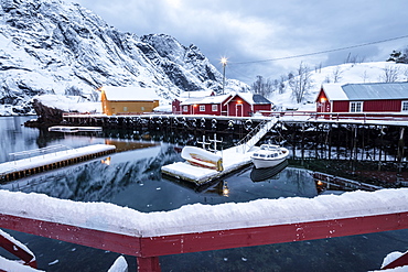 Cold sea and snowy peaks frame the fishing village at dusk, Nusfjord, Nordland, Lofoten Islands, Northern Norway, Scandinavia, Europe