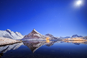 Full moon and stars light up the snow capped peaks reflected in sea, Volanstinden, Fredvang, Lofoten Islands, Northern Norway, Scandinavia, Europe