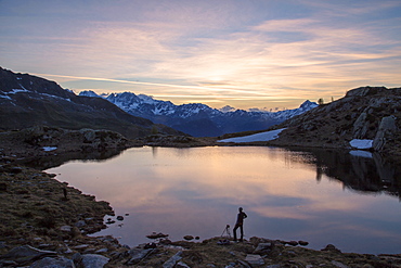 Photographer admires the pink sunrise on Lake Zana, Malenco Valley, Valtellina, Province of Sondrio, Lombardy, Italy, Europe