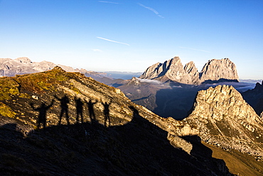 Silhouettes of hikers frame Sass Beca and Sassolungo from Cima Belvedere, Canazei, Val di Fassa, Trentino-Alto Adige, Italy, Europe