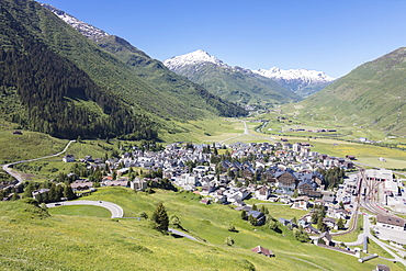 The alpine village of Andermatt surrounded by green meadows, and snowy peaks in the background, Canton of Uri, Switzerland, Europe