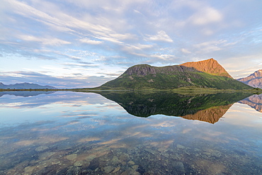 Pink clouds and peaks are reflected in the clear sea at night time, Vengeren, Vagspollen, Lofoten Islands, Norway, Scandinavia, Europe