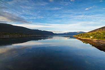 Light of the midnight sun illuminates the clear water of blue sea and green woods, Anepollen Fjord, Nordland, Norway, Scandinavia, Europe