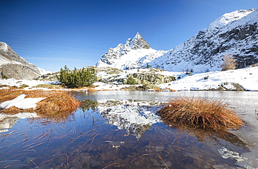 Snowy peaks are reflected in the alpine lake partially frozen, Lejets Crap Alv (Crap Alv Laiets), Canton of Graubunden, Engadine, Switzerland, Europe