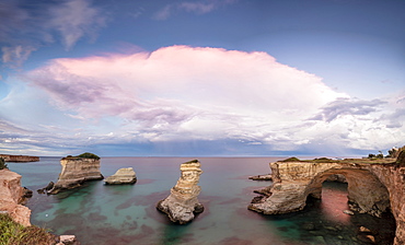 Pink sunset frames the cliffs known as Faraglioni di Sant'Andrea and the turquoise sea, province of Lecce, Apulia, Italy, Europe