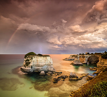 Rainbow and lightning after the storm on cliffs known as Faraglioni di Sant'Andrea, province of Lecce, Apulia, Italy, Europe