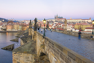 People on the historical Charles Bridge on Vltava River at dawn, UNESCO World Heritage Site, Prague, Czech Republic, Europe