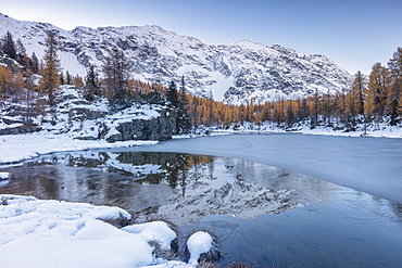 The snowy peaks are reflected in the frozen Lake Mufule, Malenco Valley, Province of Sondrio, Valtellina, Lombardy, Italy, Europe