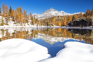 The snowy peaks are reflected in the frozen Lake Mufule, Malenco Valley, Province of Sondrio, Valtellina, Lombardy, Italy, Europe