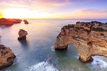 Sunrise on cliffs framed by turquoise water of the ocean, Praia da Marinha, Caramujeira, Lagoa Municipality, Algarve, Portugal, Europe