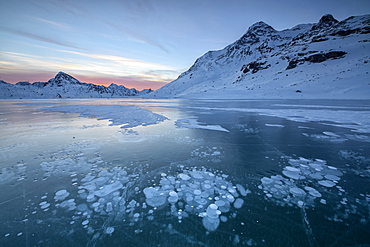 Ice bubbles frame the snowy peaks reflected in Lago Bianco, Bernina Pass, canton of Graubunden, Engadine, Switzerland, Europe