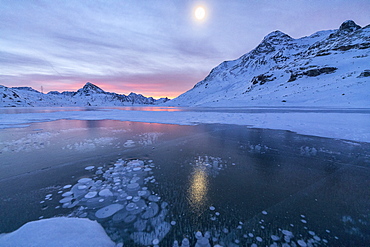 Ice bubbles frame the frozen Lago Bianco at dawn, Bernina Pass, canton of Graubunden, Engadine, Switzerland, Europe