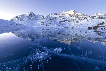 Ice bubbles frame the snowy peaks reflected in Lago Bianco, Bernina Pass, canton of Graubunden, Engadine, Switzerland, Europe