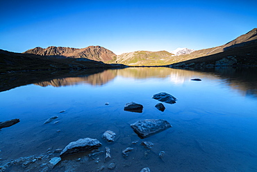 The rocky peaks reflected in Lake Umbrail at sunset, Stelvio Pass, Valtellina, Lombardy, Italy, Europe