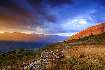 Fiery sky and dark clouds on high peaks of Muottas Muragl at sunset, St. Moritz, Canton of Graubunden, Engadine, Switzerland, Europe