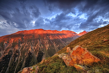 Dark clouds and sunset light frame the rocky peaks of Muottas Muragl, St. Moritz, Canton of Graubunden, Engadine, Switzerland, Europe