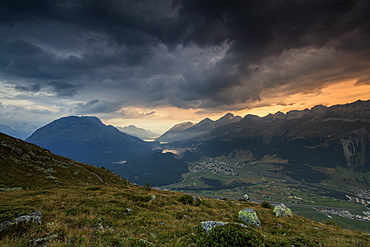 Dark clouds and sunset lights frame the rocky peaks of Muottas Muragl, St. Moritz, Canton of Graubunden, Engadine, Switzerland, Europe