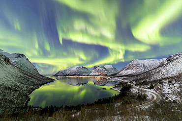 Northern lights (aurora borealis) and stars light up the snowy peaks reflected in the cold sea, Bergsbotn, Senja, Troms, Norway, Scandinavia, Europe