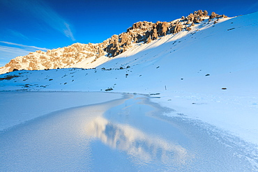 Snowy peaks reflected in the icy Lake, Piz Umbrail at dawn, Braulio Valley, Valtellina, Lombardy, Italy, Europe