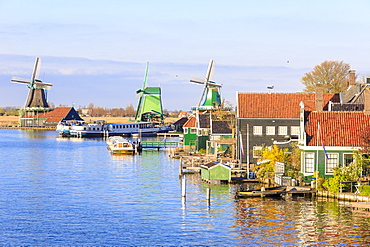 Wood houses and windmill reflected in the blue water of River Zaan, Zaanse Schans, North Holland, The Netherlands, Europe